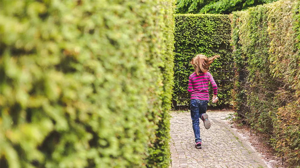 Foto von einem Mädchen das durch ein Labyrinth rennt