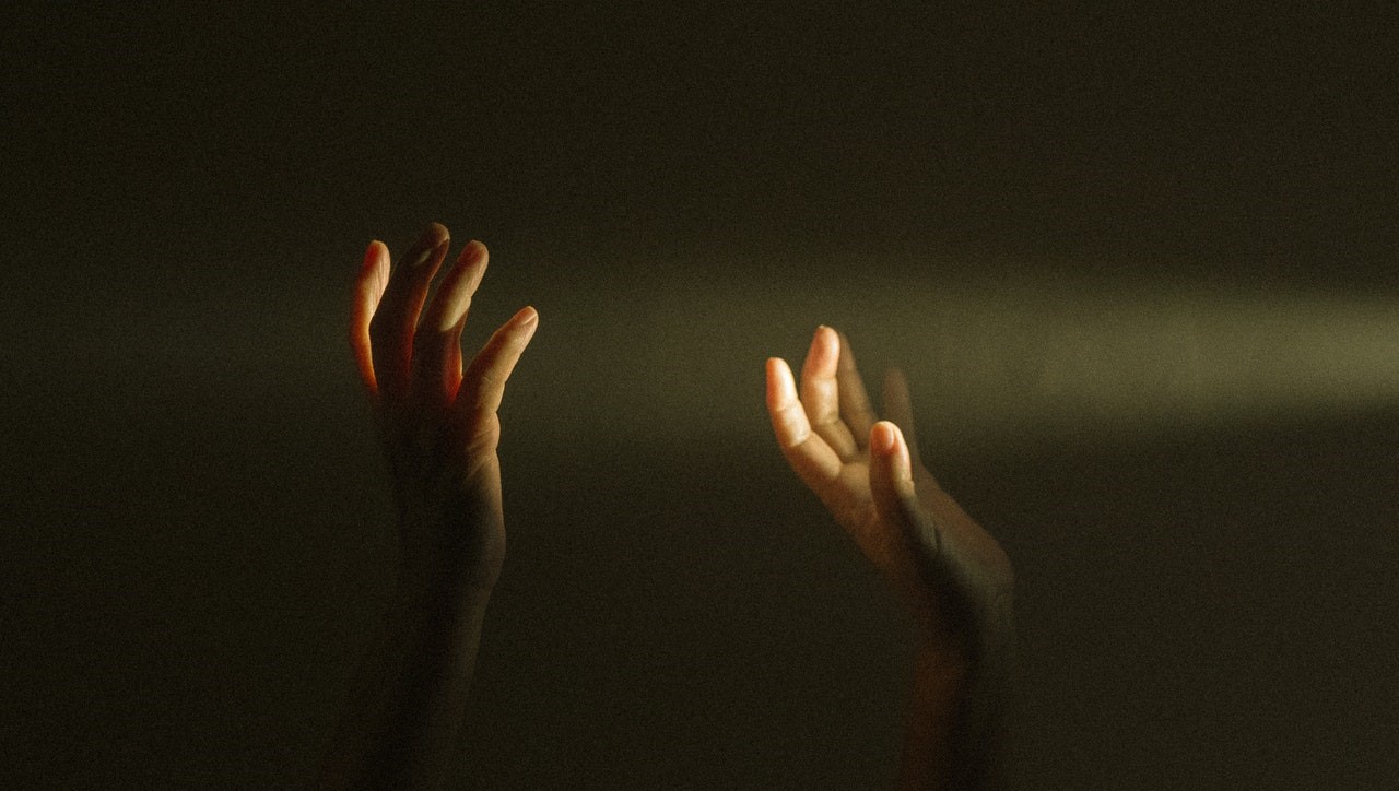 Foto von zwei Händen die Lichtstrahlen berühren